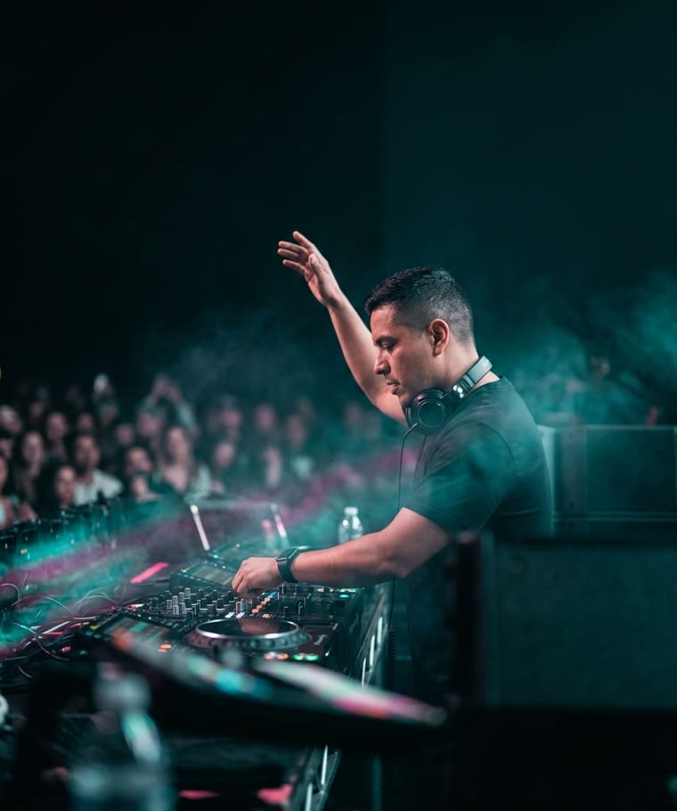 A DJ performing behind the decks in front of a crowd
